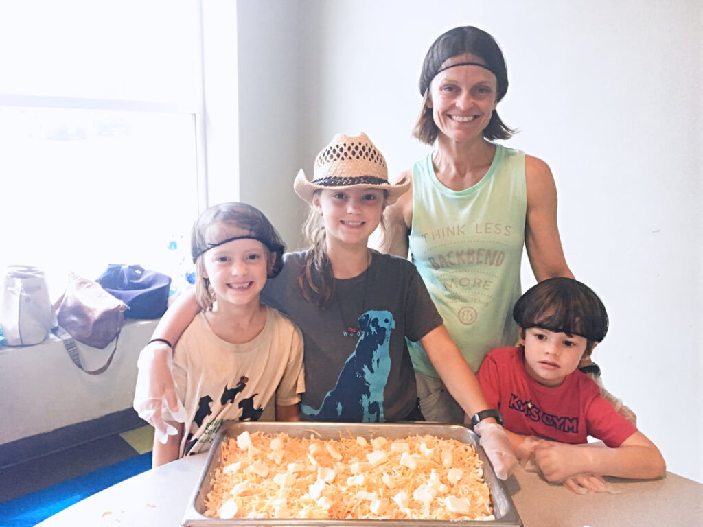 Four participants in hairnets prepare food together at a youth volunteering event.