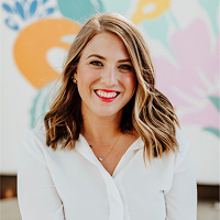Lily McClure, President, smiles before a mural promoting youth volunteer programs.