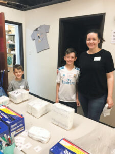 A family participates in youth volunteer programs Texas, packing boxes together.
