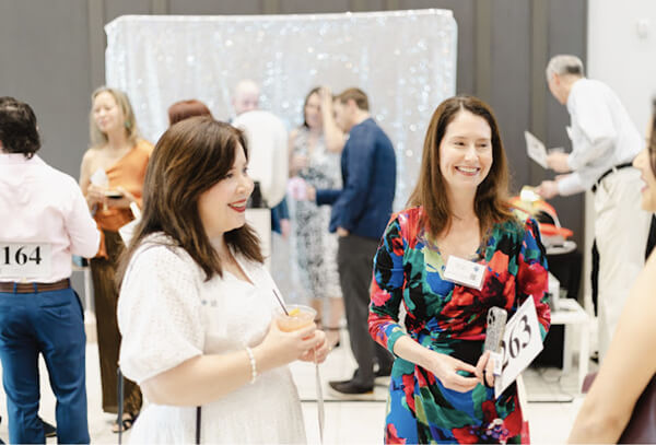 Two women discuss youth volunteer programs at a Texas teen service fundraiser event.