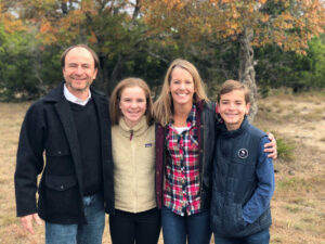 Four people smile outdoors, representing youth and family volunteering in Texas.