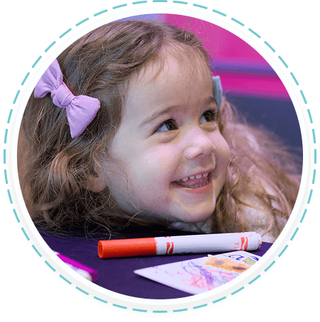 Smiling young girl volunteers in Texas youth program, drawing at activity table.