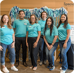 Six youth volunteers in teal shirts smile at a teen service event in Texas.