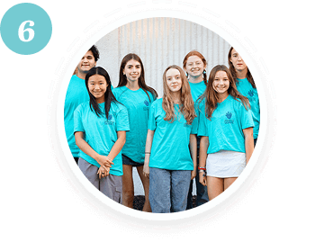 Seven teens in matching shirts smile, representing youth volunteer programs Texas.
