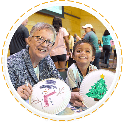 A woman and boy smile with crafts, showing youth and family volunteering in Texas.