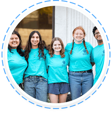 Five teens in turquoise shirts smile while volunteering in a Texas youth program.