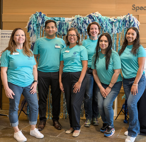 Six teen volunteers in matching shirts smile at a youth volunteering event in Texas.