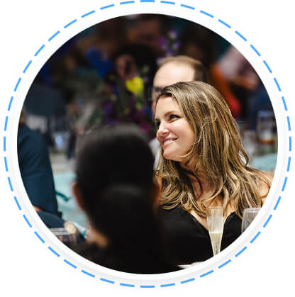 A woman with light brown hair smiles at a table during a youth volunteer program in Texas.