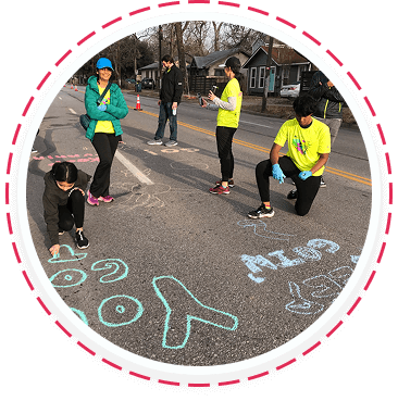 Teens and families volunteer in Texas, drawing chalk messages during a youth service event.