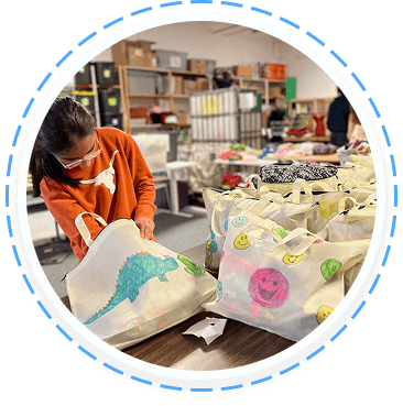 A volunteer packs illustrated tote bags at a youth volunteer program in Texas, showcasing teen service and family volunteering opportunities.