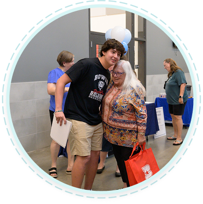 A teen service volunteer and elder at a Texas family volunteering event indoors, showing youth volunteer programs supporting seniors.