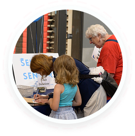 An adult woman signs a paper as a teen and elderly woman look on, showing youth volunteer programs and family volunteering opportunities Texas.