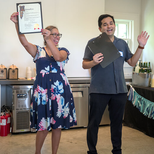 A woman in a floral dress celebrates a youth volunteering award with a man at a Texas teen service volunteer program event.