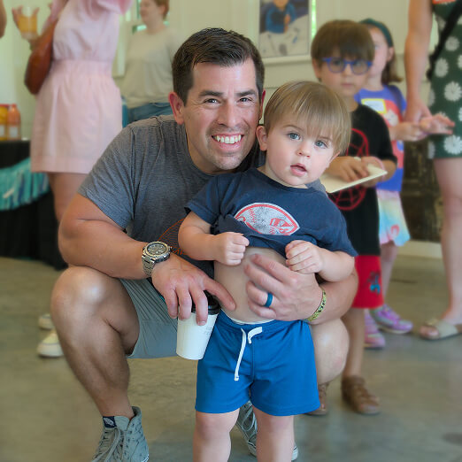 A volunteer adult smiles beside a young boy at a youth service event in Texas, promoting family volunteering opportunities and teen volunteer programs.